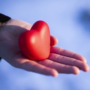 Woman holding heart-shaped snowball, close-up of hands