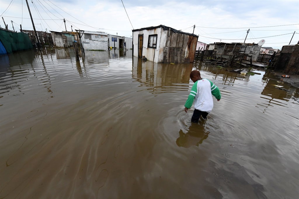 A boy walks through knee-deep pools of water at Nomakanjani Informal Settlement on June 28, 2023 in Gqeberha. 