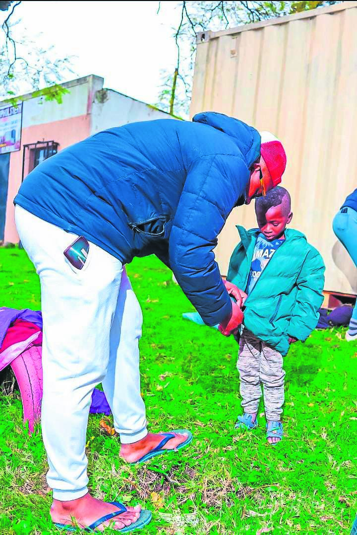 Azole Jezile helps one of the recipients put on his new jacket.