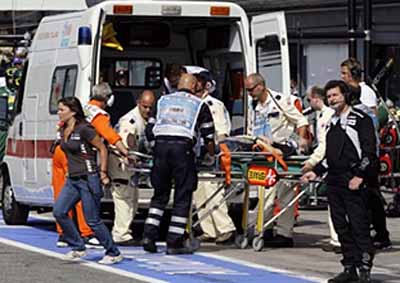 PAIN IN THE PITS: The injured Hispania team pit crew member is loaded into an ambulance.