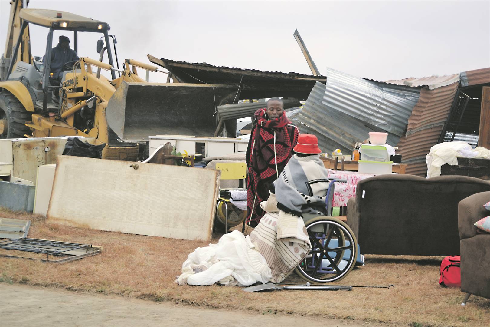 Tsholo Mopeli and Roseline Kupe watch as a bulldoz