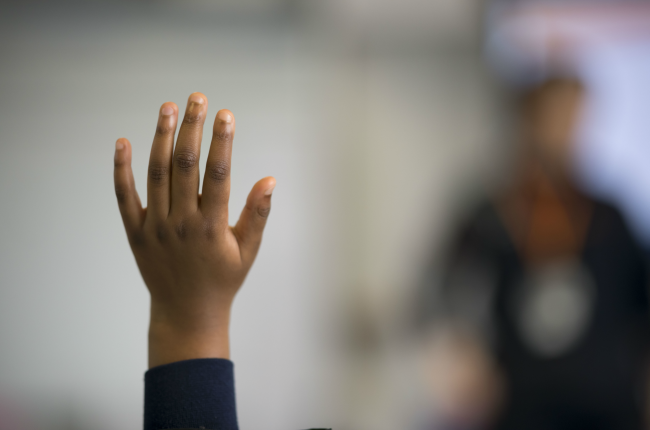 A child holds their hand up in classroom