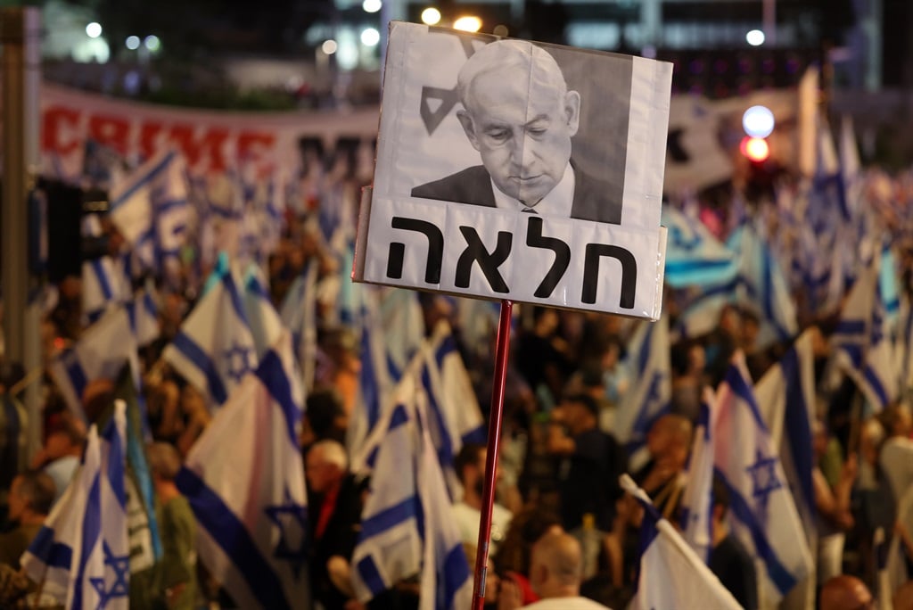 Protesters lift a placard bearing a picture of Prime minister Benjamn Netanyahu as they march against the Israeli government's judicial overhaul plan in Tel Aviv on July 29, 2023. 