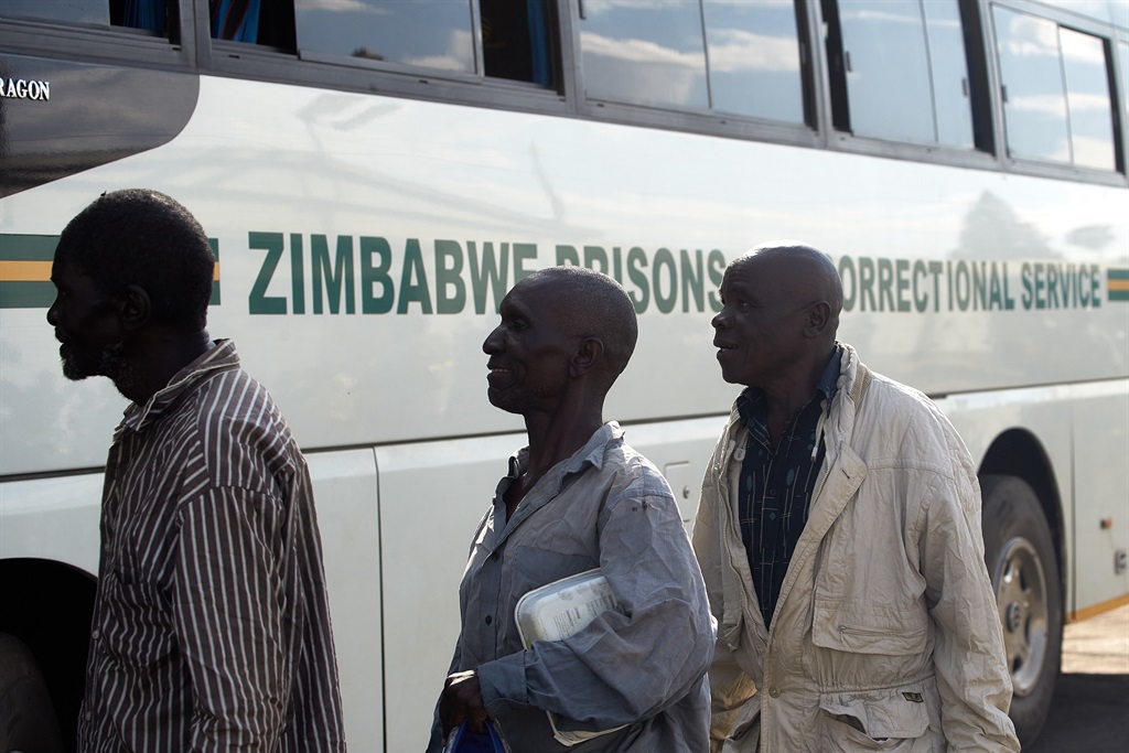 Former inmates queue to board a bus as they head h