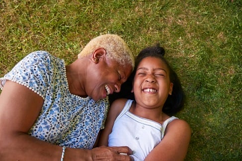 Black girl and grandmother lying on grass, overhea