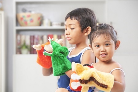 Asian sibling playing hand mad hand-puppet at home