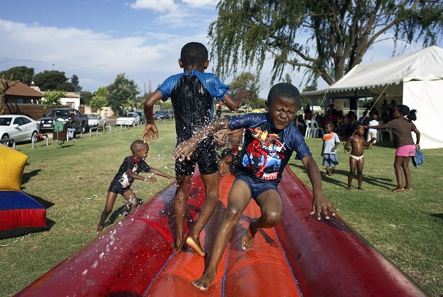 Children making friends through play on a jumping castle during a birthday celebration in Soweto.
