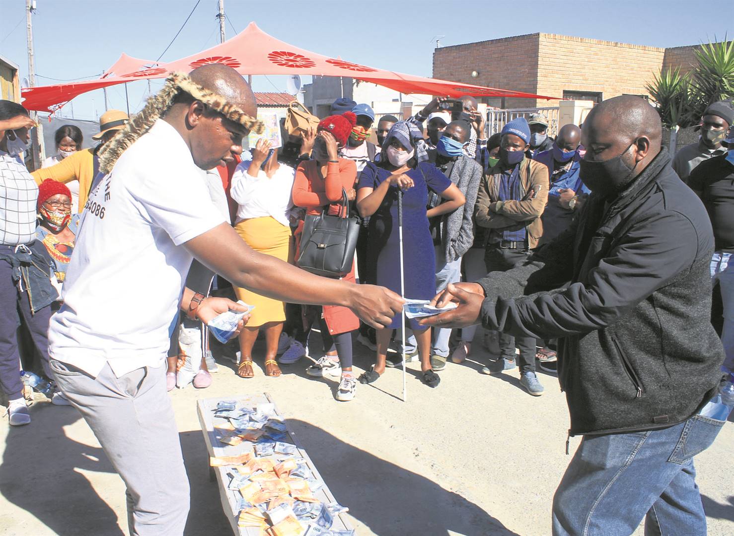 Sibusiso ‘Mkhulu’ Mathe, a sangoma from Makhaza in Khayelitsha, hands out money to residents.         Photo by Lindile Mbontsi