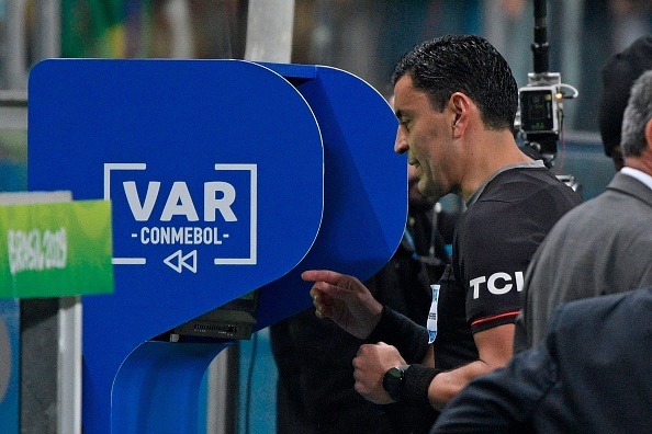 Chilean referee Roberto Tobar checks the VAR to show the red card 