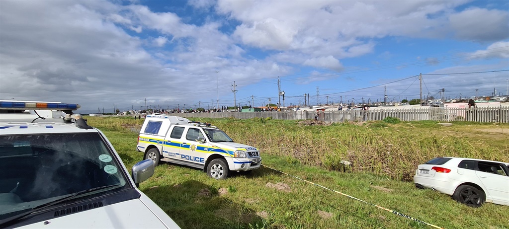 Massive police contingent surround an Audi which had left the road and plunged into a shallow ditch at Khayelitsha.