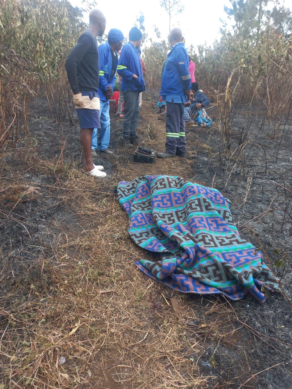 Tragic: Villagers at the scene where the body of gogo (66) was found.