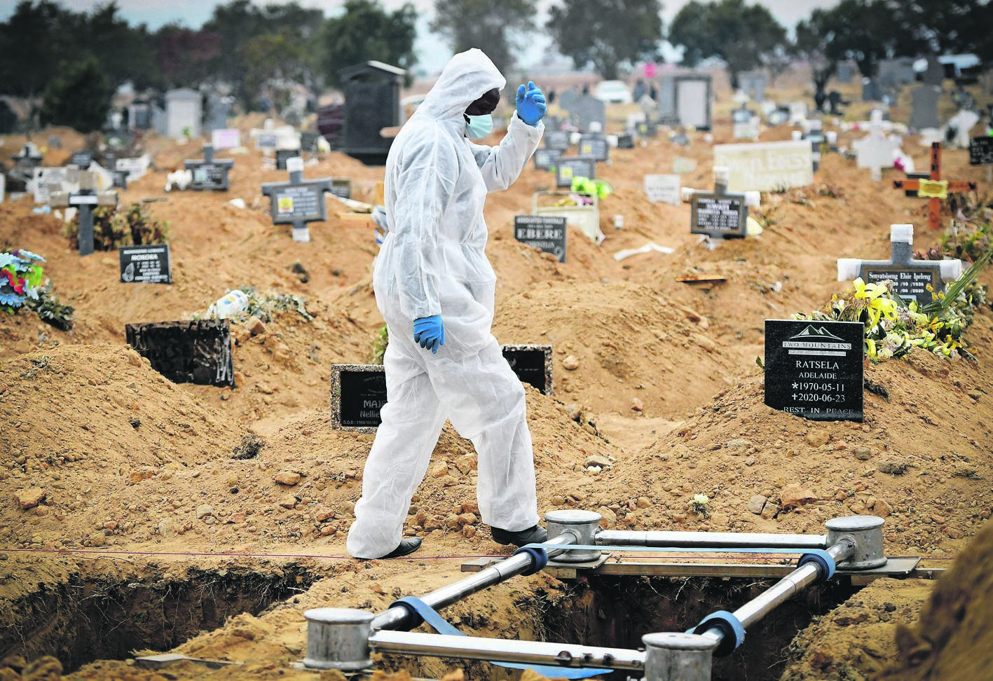A funeral parlour staff member in personal protective gear prepares a grave for a Covid-19-related burial. 