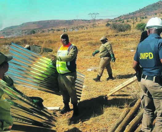 Metro cops demolish illegal shacks in an open field near Lenasia South yesterday. 