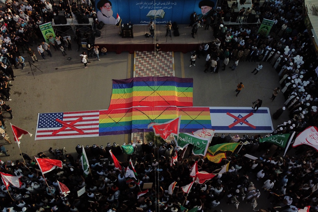 Iraqi Shiite Muslims prepare to set ablaze signs representing the flags of the US, the LGBTQ+ community and Israel, during a protest in Nasiriyah on 4 July 2023 against a Koran burning outside a Stockholm mosque that outraged Muslims around the world.