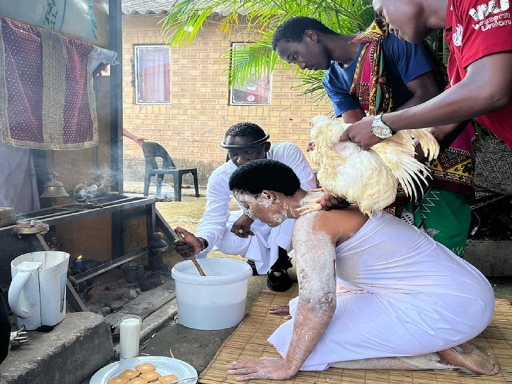Zodwa Wabantu wearing white with her gobela Sifiso Mhlaba, who died on Sunday, squatting next to her. 