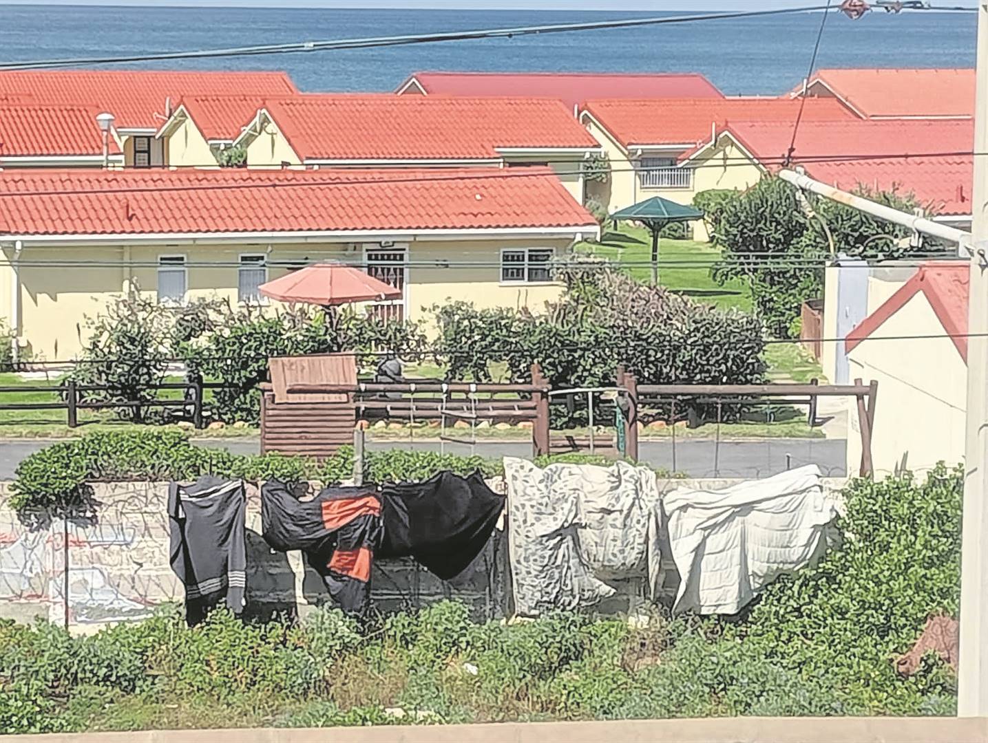 Blankets and tents hung over a wall next to the railway line, between South Shore and beach apartments in Fish Hoek where street people slept. PHOTO: Supplied