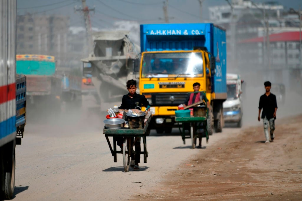 People make their move in a dusty busy road in Dhaka, Bangladesh, on June 24, 2023. 