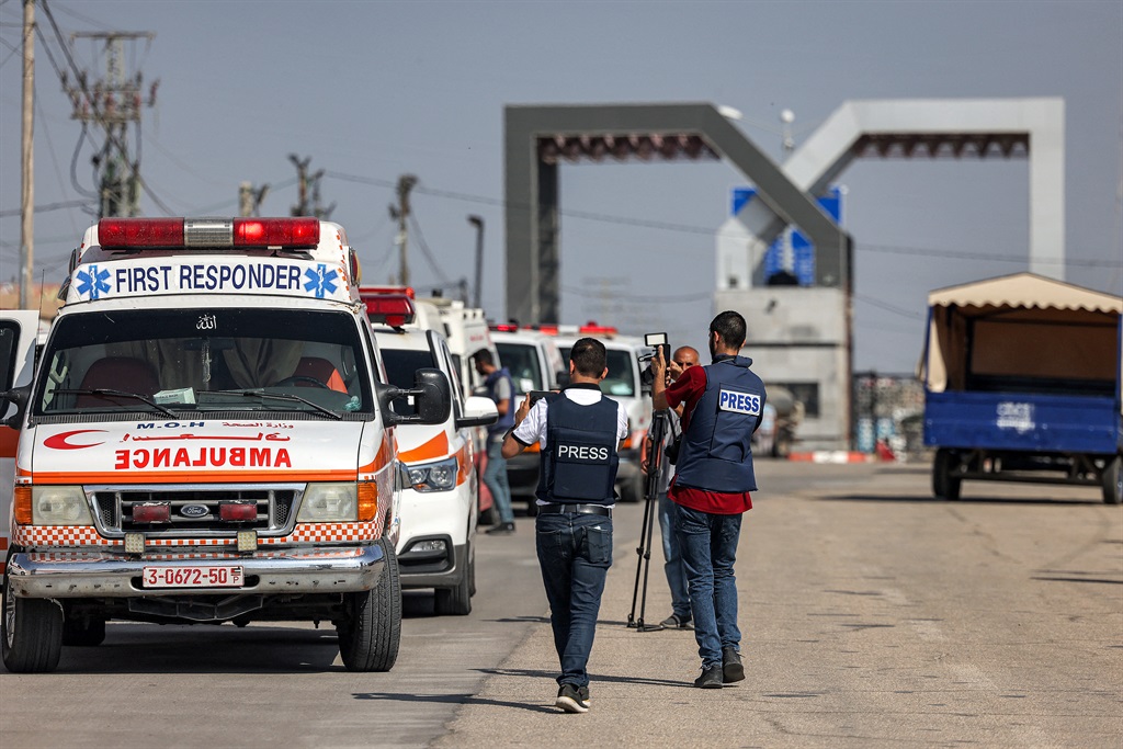 Journalists film as Palestinian health ministry ambulances cross the gate to enter the Rafah border crossing in the southern Gaza Strip before crossing into Egypt on 1 November 2023. 