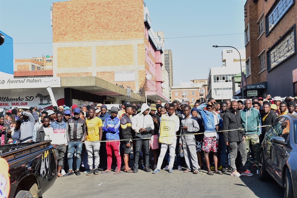 Survivors and onlookers near a suspected hijacked building that was gutted by fire in the Joburg CBD. Photo by Morapedi Mashashe