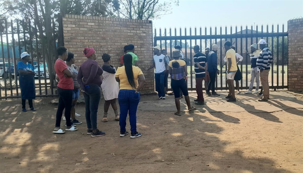 Angry residents who are demanding the removal of the principal standing outside the school gate. Photo by Tumelo Mofokeng