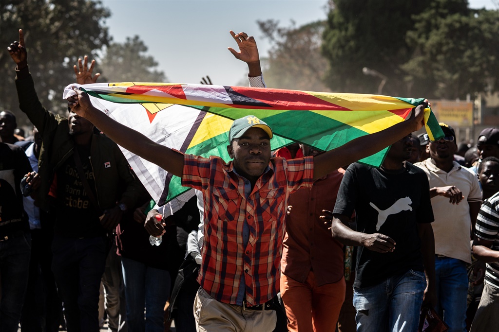 A man holding Zimbabwe's national flag walks with 