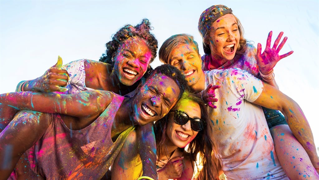 happy young multiethnic friends with colorful paint on clothes having fun together at holi festival