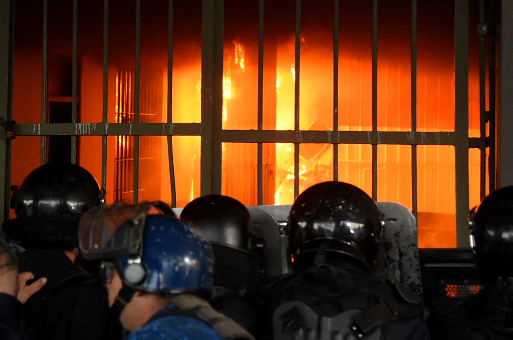 Security forces look as fire burns inside the Tacumbu prison after hundreds of inmates took the facility, in Asuncion, on October 10, 2023. 