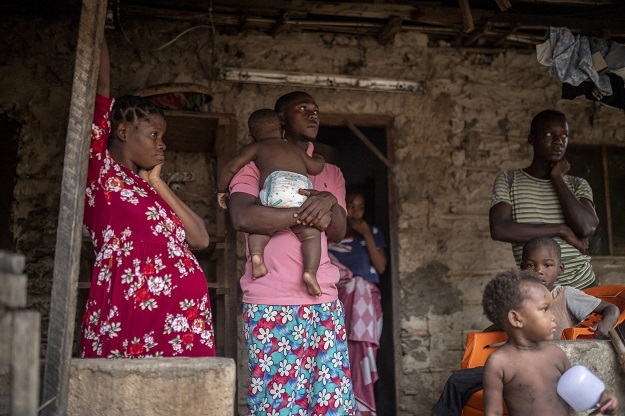 A displaced family looks on in front of a house in Paquitequete, Mozambique, where thousands of people have been displaced.