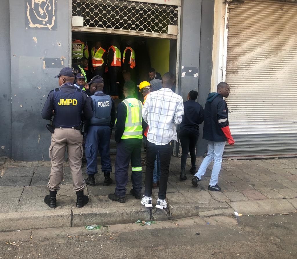 Metro cops, police and residents outside one of the hijacked buildings in the Joburg CBD where City Power workers were disconnecting illegally connected electricity on Wednesday. 