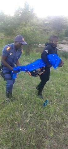 A cop and Fire and Rescue team member Cockroach Mdluli carrying the body of Vuyo Khoza retrieved from the local river on the outskirts of Justicia Village. Photo by Oris Mnisi