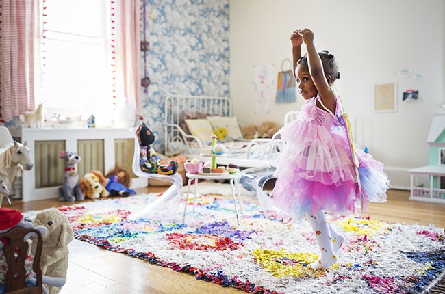 A child dressed up as a fairy dances in her room.