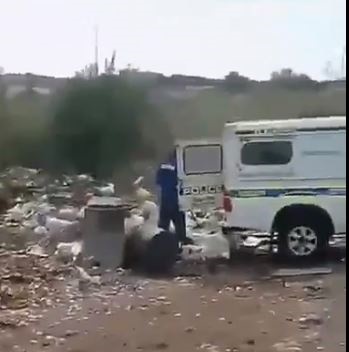 A man wearing blue overalls is seen dumping rubbis