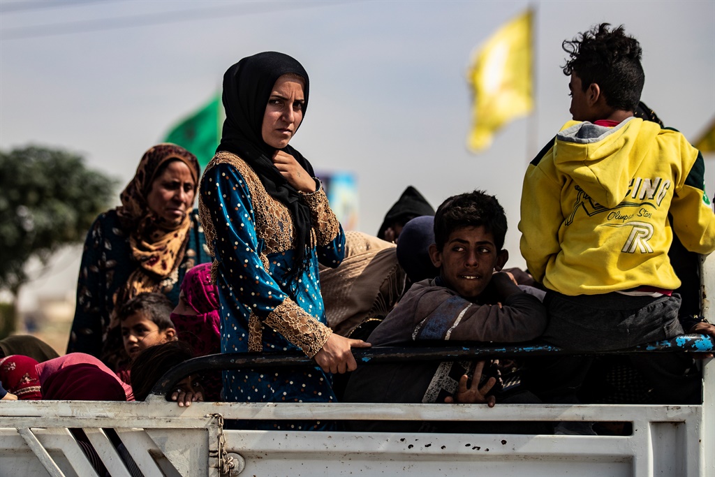 Displaced Syrians sit in the back of a pick up tru