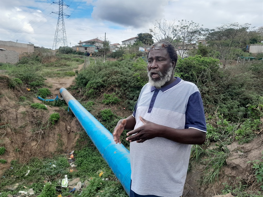 Zakhele Sibeko showing the water pipe they use to get to the other side of their area. Photo by Mbali Dlungwana