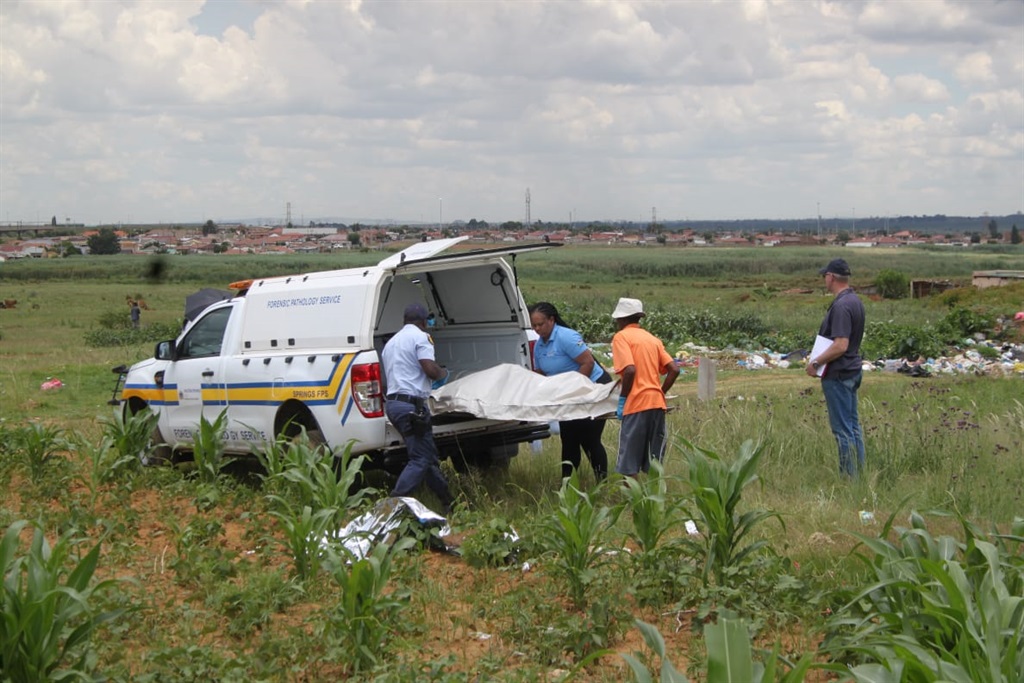 The body of the man is being loaded onto the back of a mortuary van. Photo by Phineas Khoza