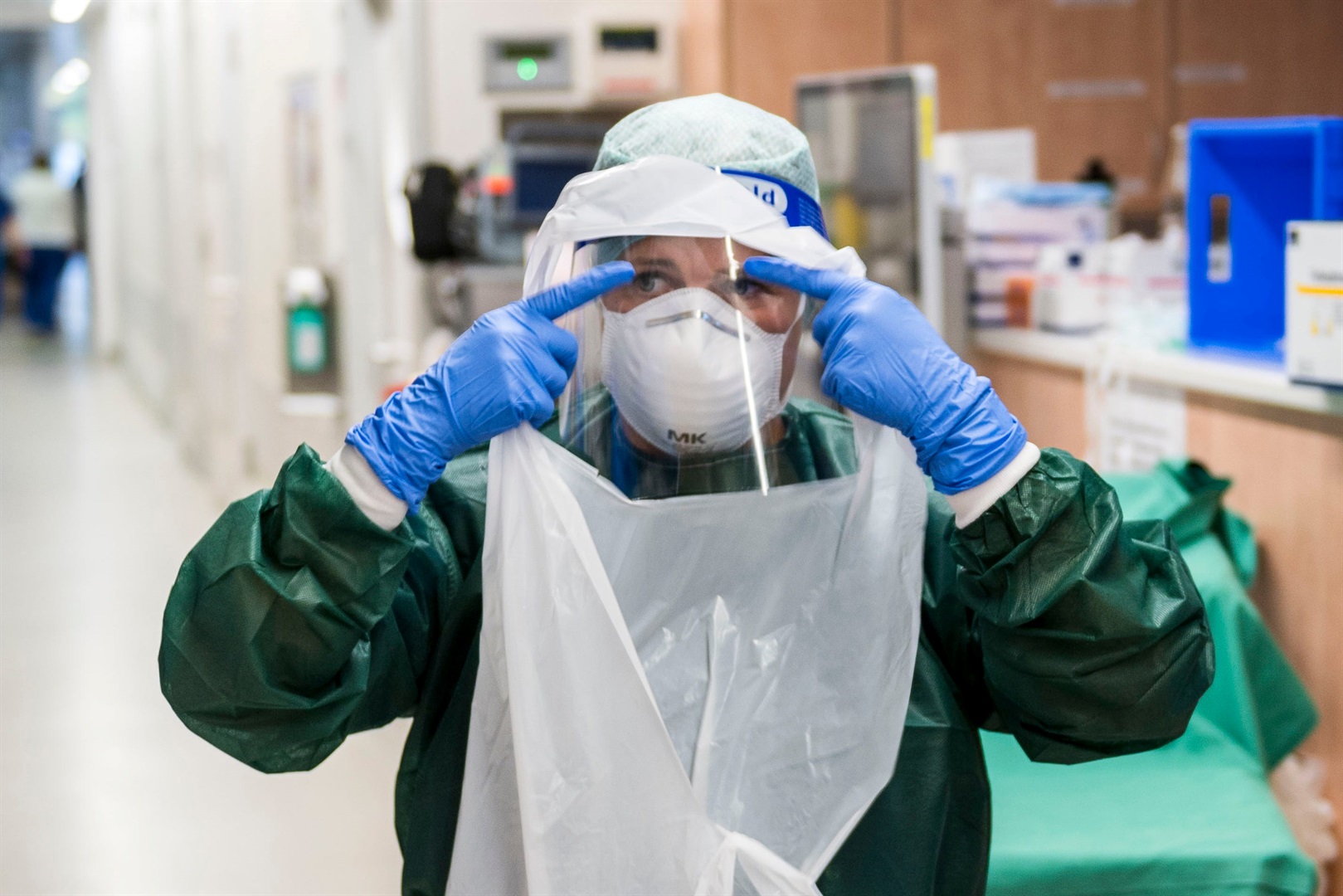 A nurse puts on PPE before tending to a Covid-19 patient.