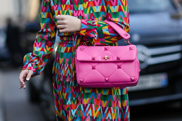  A guest wears a multicolored print pattern long dress, a pink shiny leather nailed / studded handbag from Valentino, outside Valentino, during Paris Fashion Week - Womenswear F/W 2022-2023 in Paris, France. Photo by Edward Berthelot/Getty Images