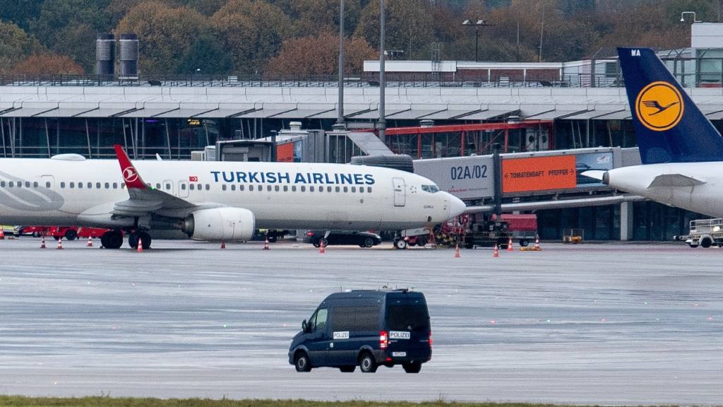 A police van observes the car of a hostage taker seen parked under a Turkish airline plane on the tarmac at the airport in Hamburg, northern Germany.