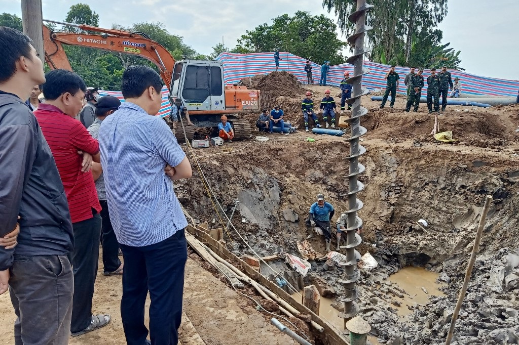 Rescuers look down into the site of where a 10-year-old boywas trapped in a 35-metre deep shaft at a bridge construction area in Vietnam's Dong Thap province on January 2, 2023.