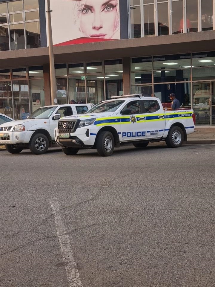 Police bakkies in front of the stores, with police officers loading alleged stolen property. Photo by Mohanoe Khiba 
