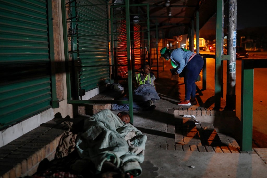 A homeless man sleeps while Statistics South Africa fieldworker conducts a survey on another during the population and housing census at Marabastad in Pretoria on 3 February 2022.