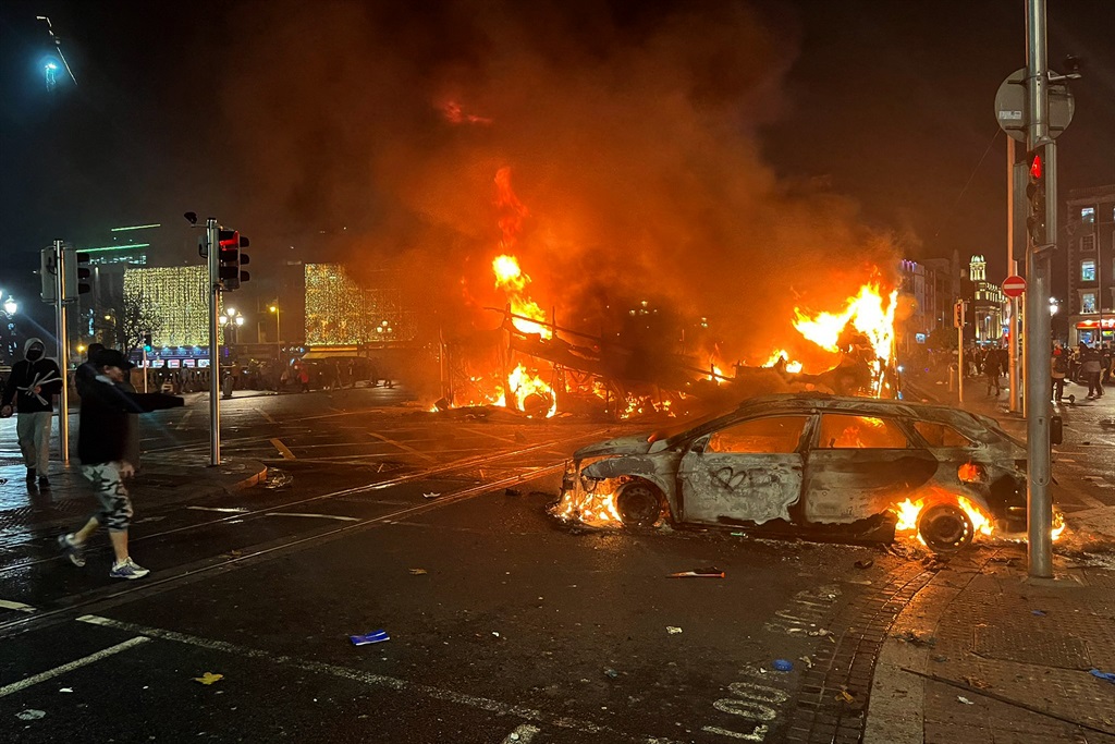 Flames rise from the car and a bus, set alight at the junction of Bachelors Walk and the O'Connell Bridge, in Dublin on November 23, 2023, as people took to the streets following the stabbings earlier in the day. 