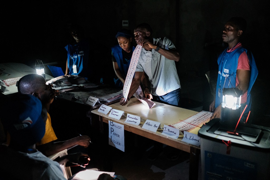 Election officials count ballots at a polling station in Monrovia on 10 October 2023. (Photo by GUY PETERSON / AFP)