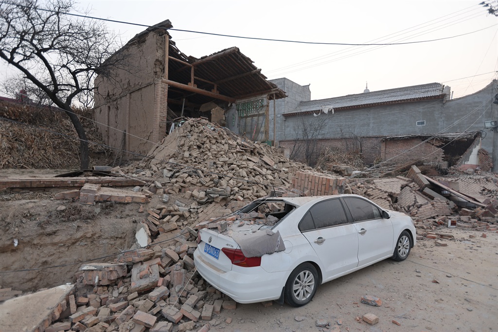 Collapsed buildings and a damaged car are seen aft