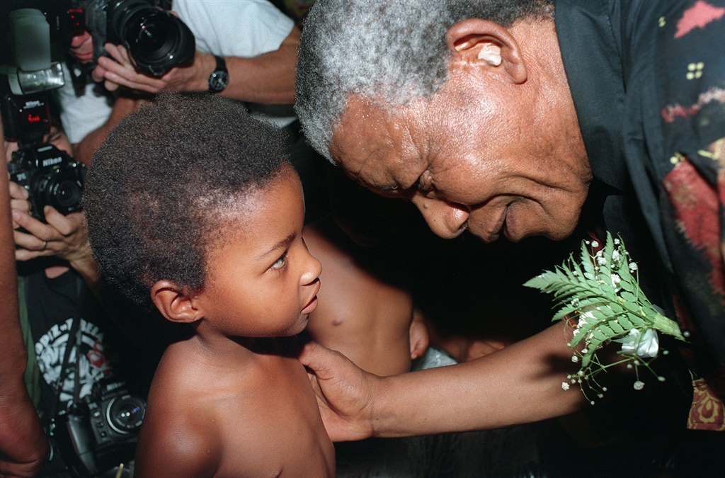 Nelson Mandela greets a young child. (Getty Images)