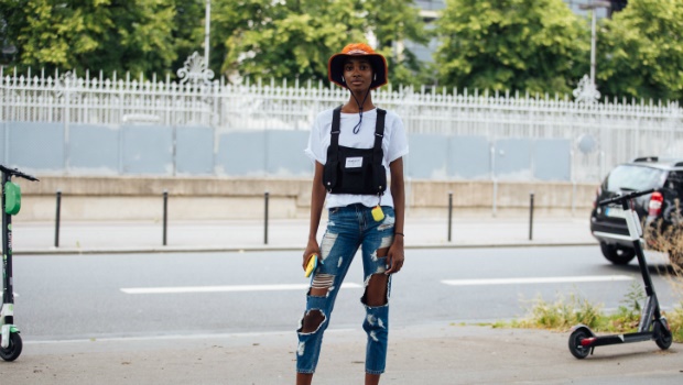 Model Tami Williams wears an orange outdoors hat, Airpods, a white top, black RoadRage by King Collection black tactile chest rig bag, yellow Airpod case at Paris Fashion Week Men's Spring/Summer 2020. Photo by Melodie Jeng