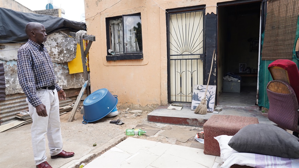 The father of one of the survivors stands outside his son's room, where the mob ransacked the place looking for his son.