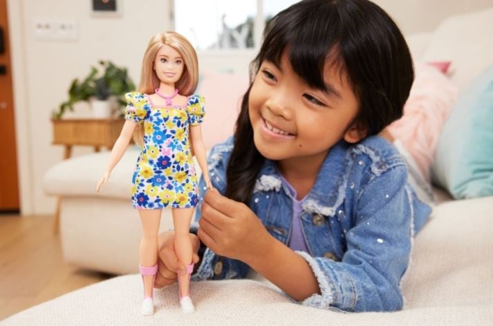 Little girl with Down Syndrome plays with Barbie doll that represents her. 