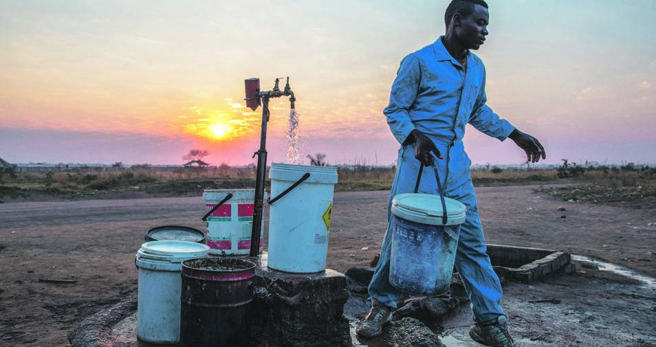 A Zimbabwean fills containers with water at a communal tap as the sun sets in Empompini in Cowdray Park, Bulawayo. The country is in the grips of a drought that has depleted dams, cut output by hydropower plants, caused harvests to fail and prompted the government to appeal for $464 million in assistance. Picture: Getty images