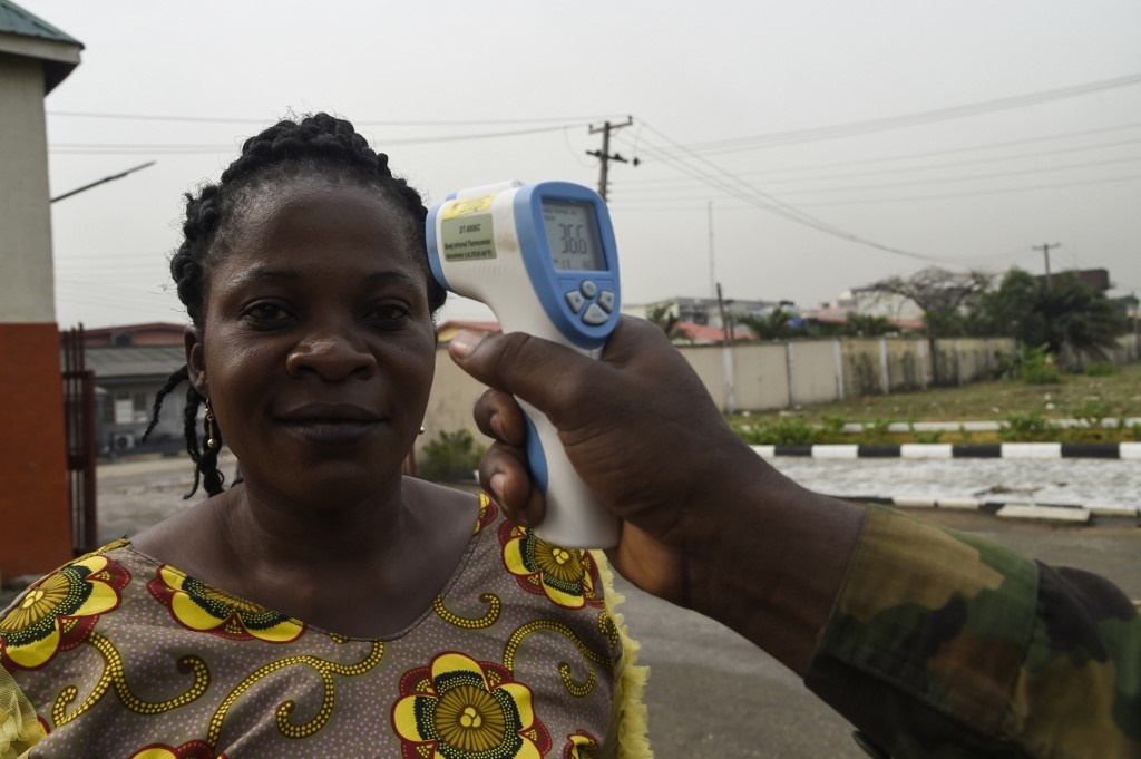 A soldier checks the body temperature of a visitor